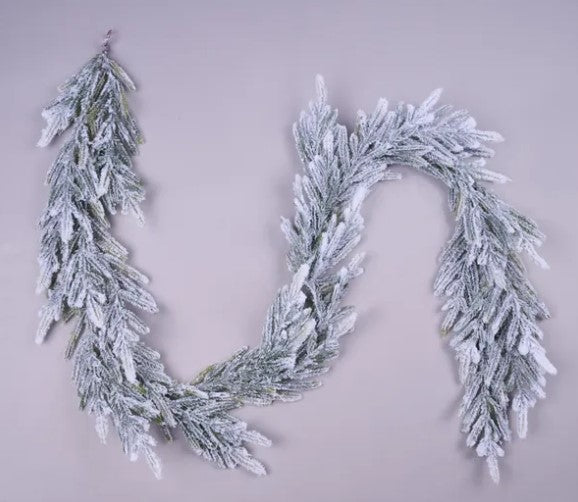 A snowflake-like garland made of small, white branches or leaves, creating a wavy, decorative pattern against a light background.