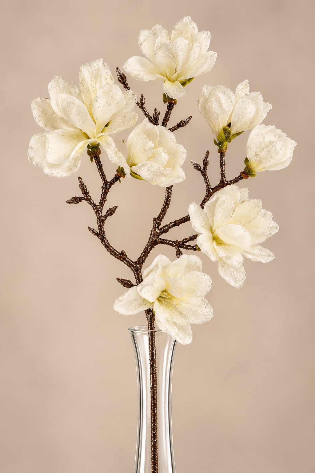 A bouquet of delicate white flowers in a clear glass vase, set against a neutral background.