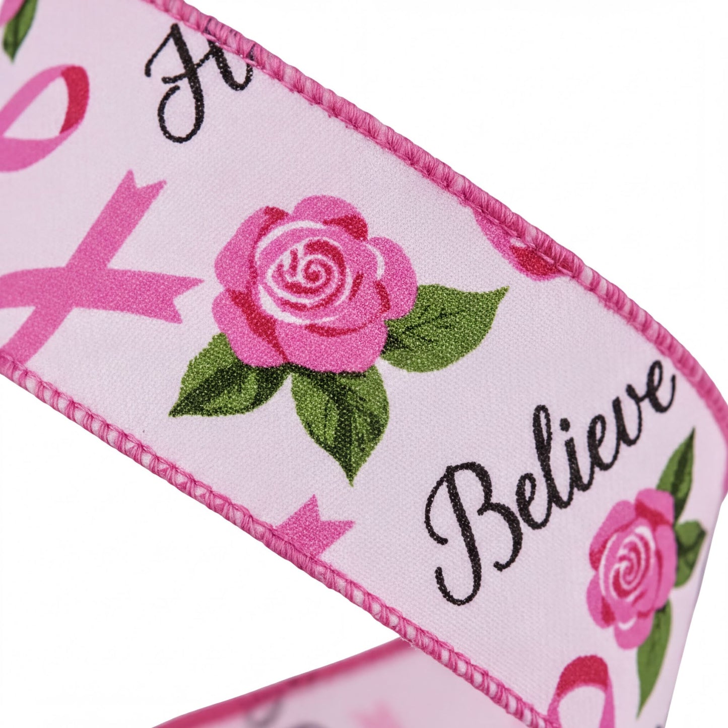 a pink ribbon with a rose design and the word "Believe" printed on it.