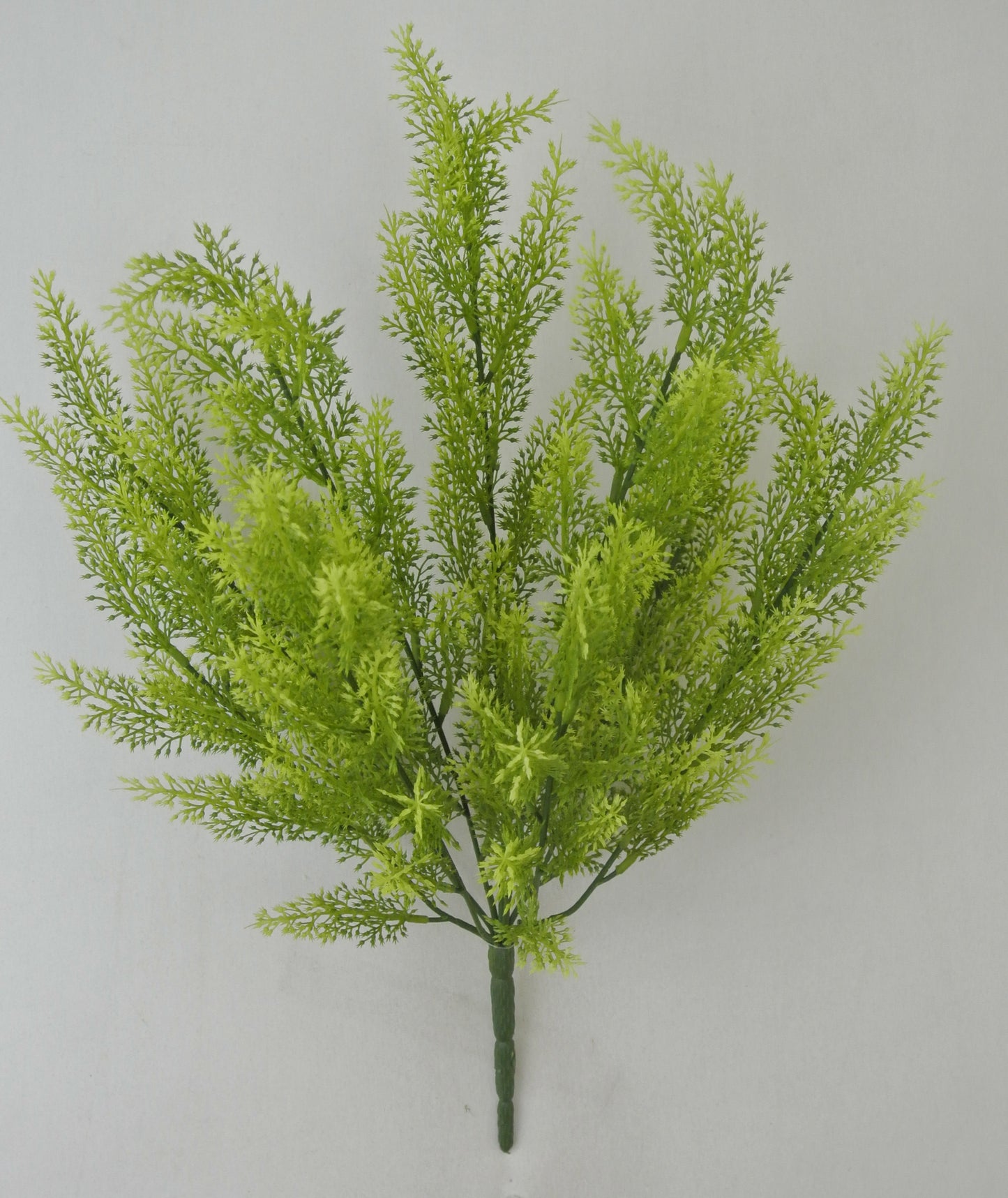 A green artificial plant with long, thin leaves arranged in a cluster.