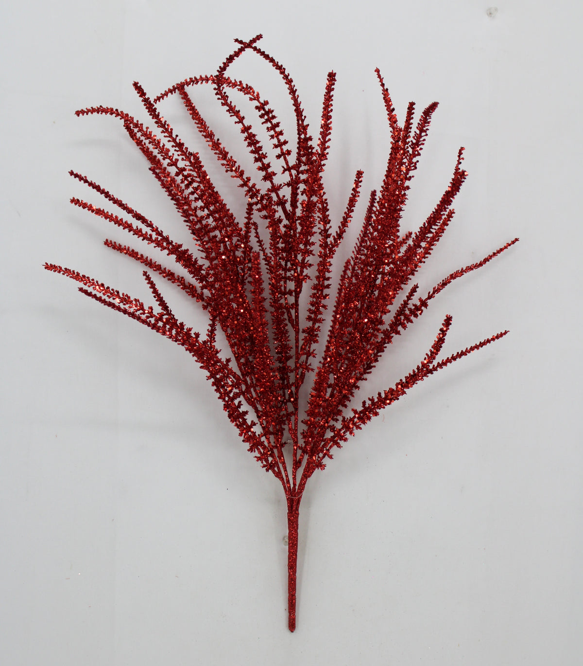 A single red, glittery branch with numerous small, thin, and delicate leaves or flowers.