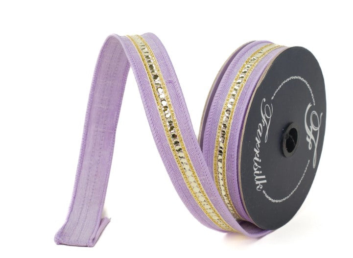 A spool of purple and gold ribbon with a metallic embellishment is shown against a white background.