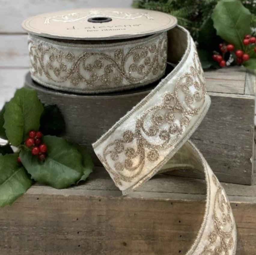 a decorative white ribbon with a gold floral pattern, placed on a wooden surface alongside some red berries and green leaves.