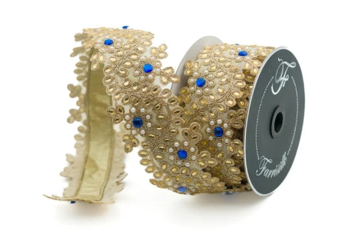 a decorative ribbon with a gold and blue floral pattern. The ribbon is coiled and has a spool of ribbon visible in the background.