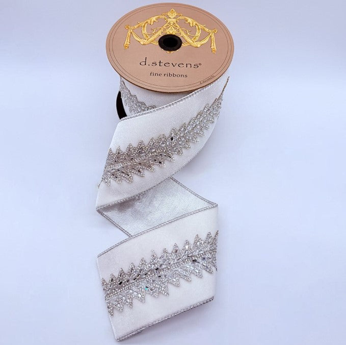 A spool of ribbon with a decorative pattern of silver and white embellishments, placed on a plain white background.