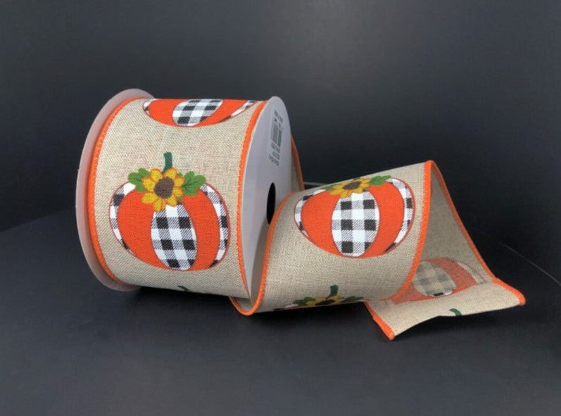 A roll of burlap ribbon with a pumpkin and sunflower design printed on it, sitting on a dark surface.