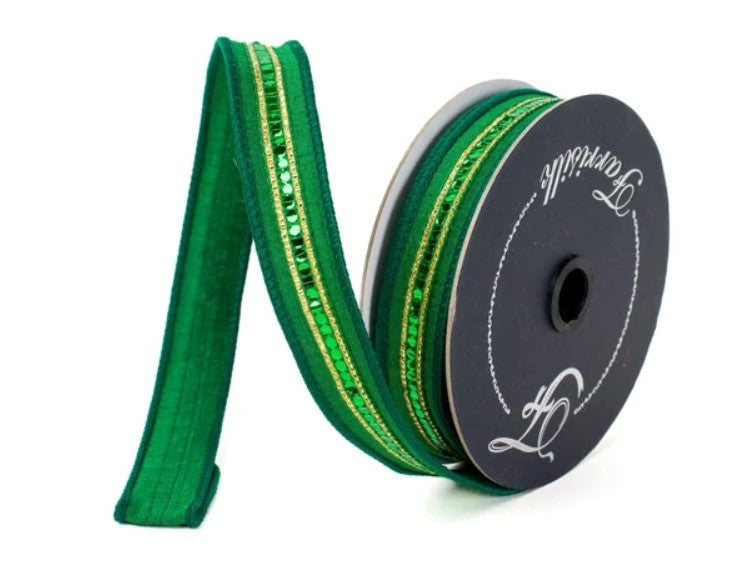 A spool of green and gold ribbon with a black and white label on it.
