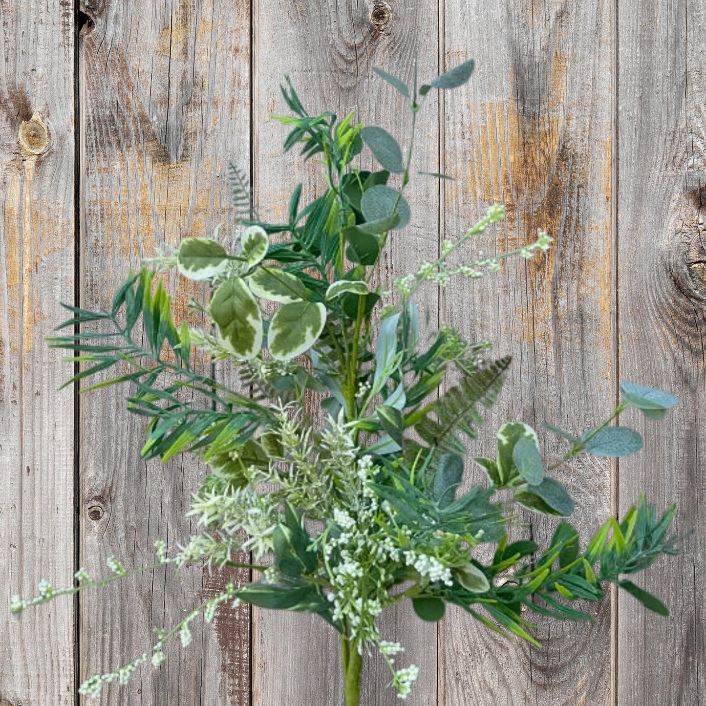 A lush arrangement of green leaves and flowers is displayed against a weathered wooden background.