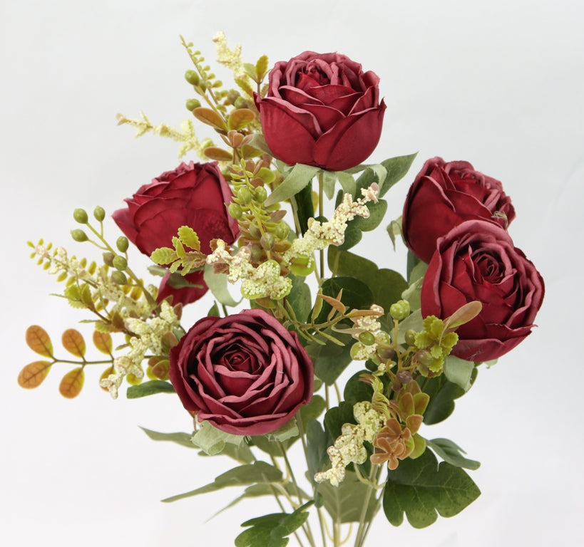 a vase filled with red roses and greenery