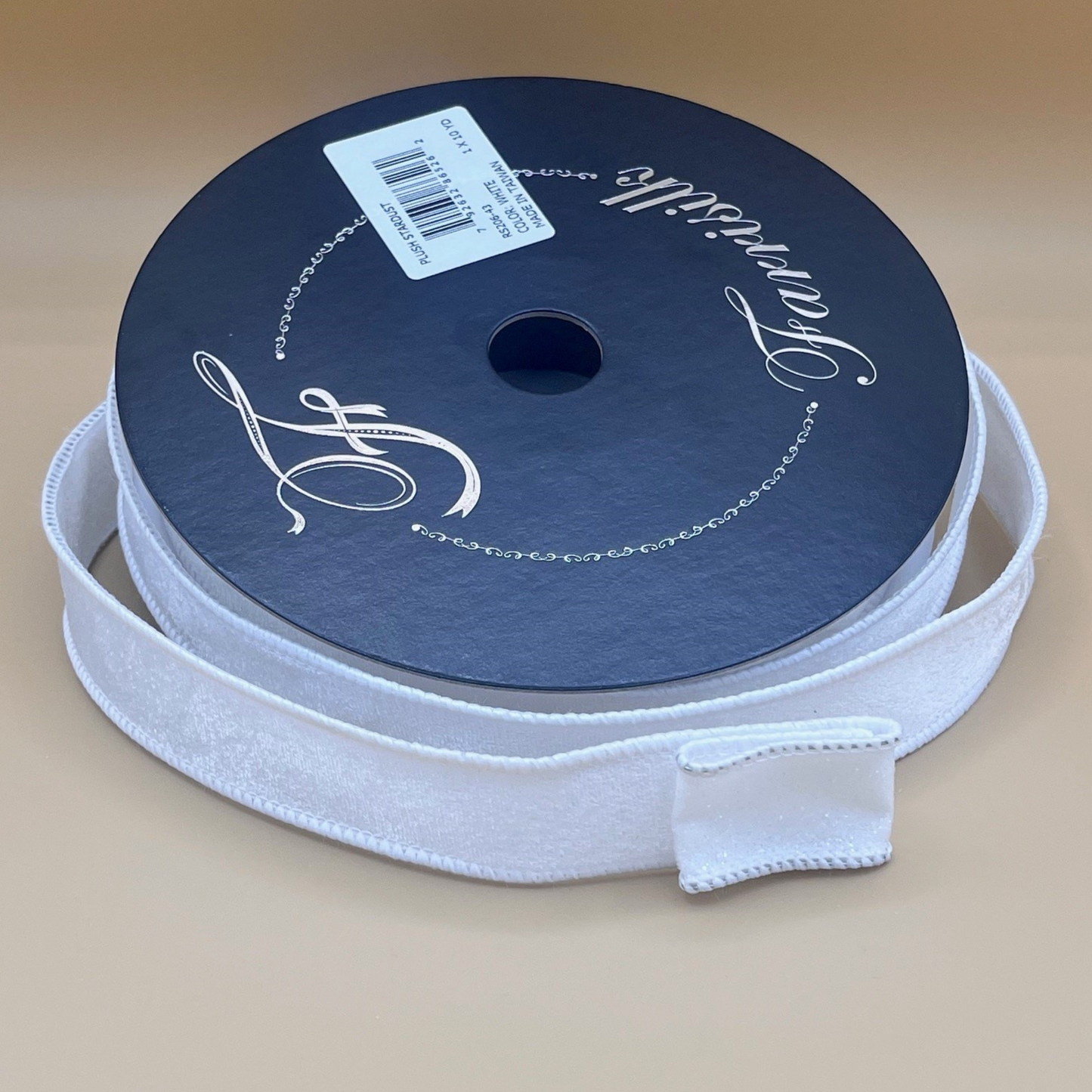 A roll of white ribbon with a black label on it, placed on a beige surface.