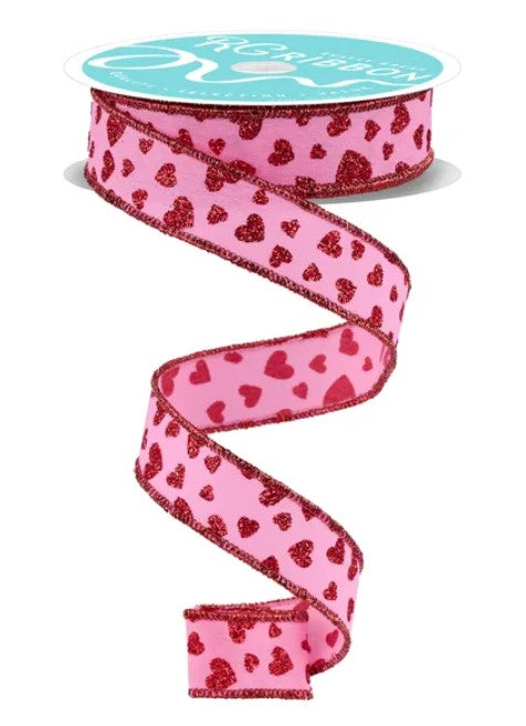 A pink ribbon with a heart pattern is shown, with a turquoise spool of ribbon visible at the top.