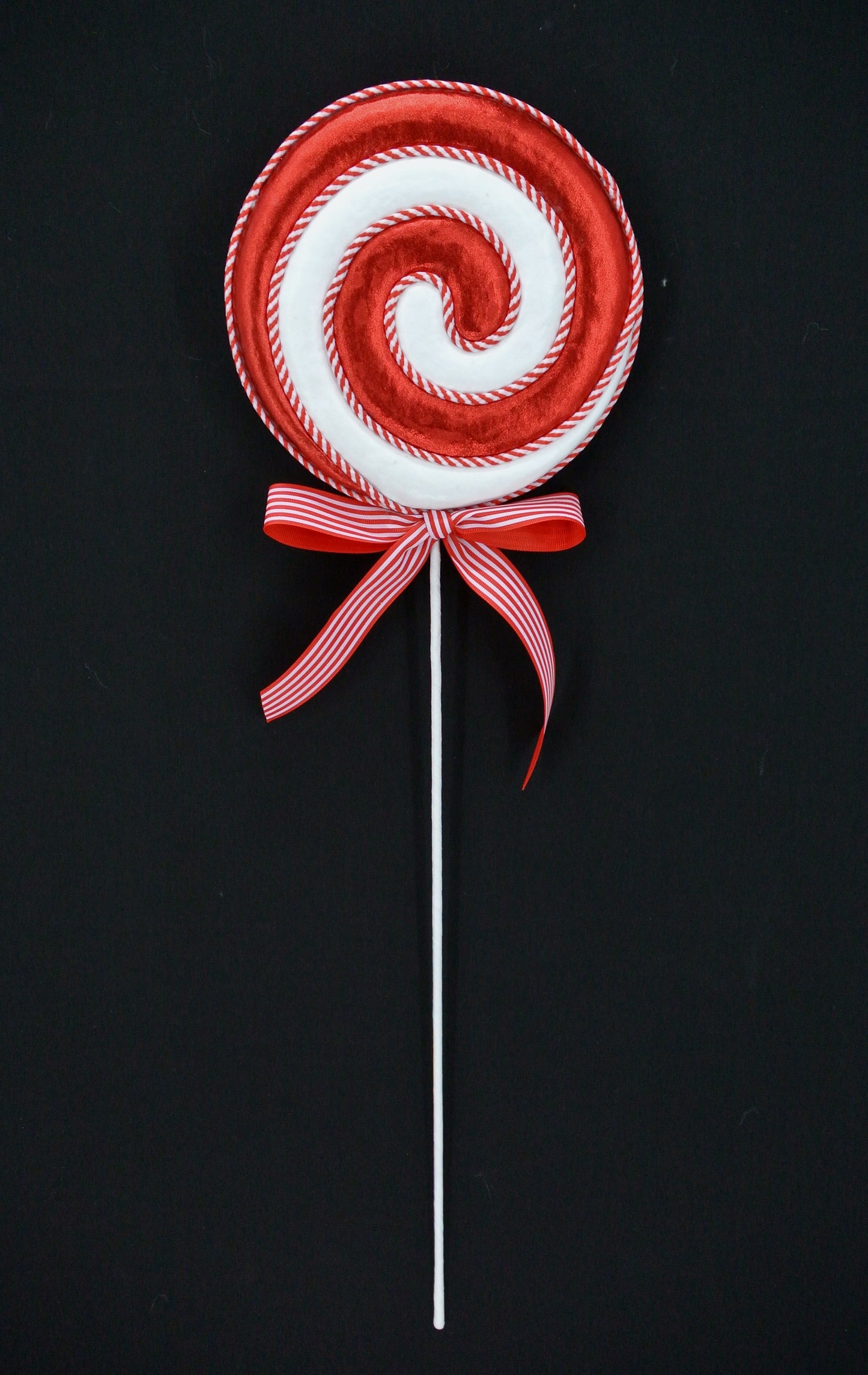 A red and white lollipop with a red ribbon tied around it, against a black background.