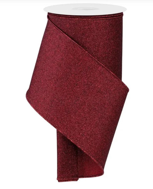 A roll of burgundy glittery ribbon is shown against a white background.