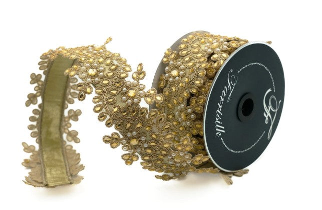 a gold-colored decorative ribbon with a floral pattern, which is coiled and attached to a spool.