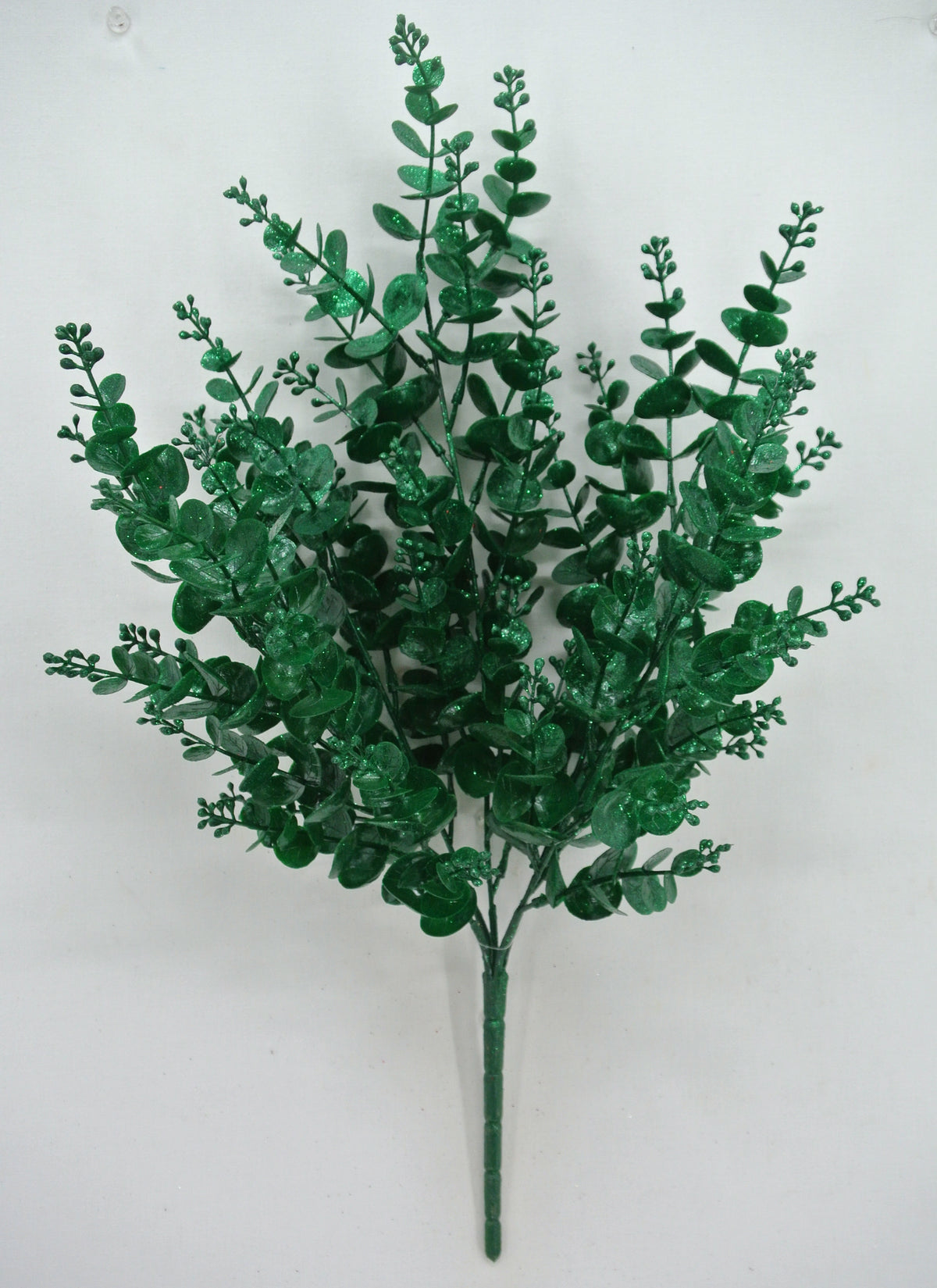 A bunch of green artificial leaves or branches, resembling a plant or a decorative element, is displayed against a white background.