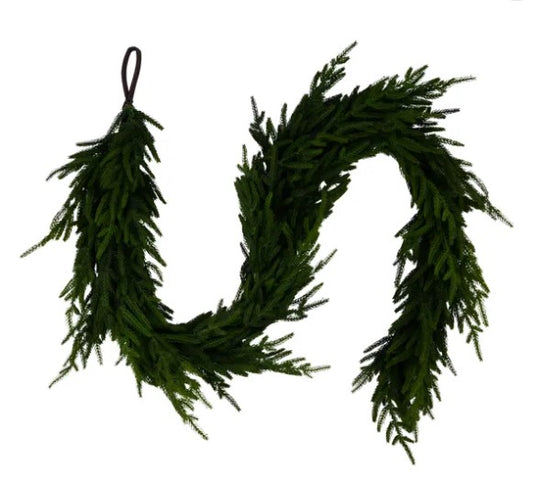 A lush, green wreath made of evergreen branches, hanging against a white background.