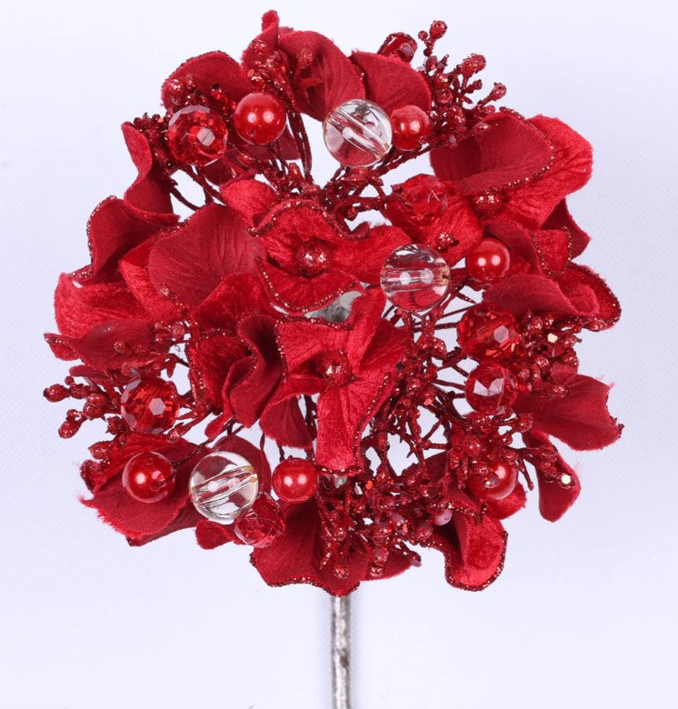 A bouquet of red flowers adorned with clear beads and round ornaments.