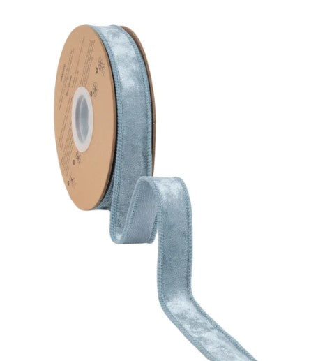 A roll of light blue velvet ribbon with a white center is shown against a white background.