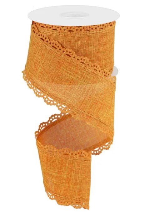 a spool of orange fabric with a scalloped edge and a lace-like pattern.