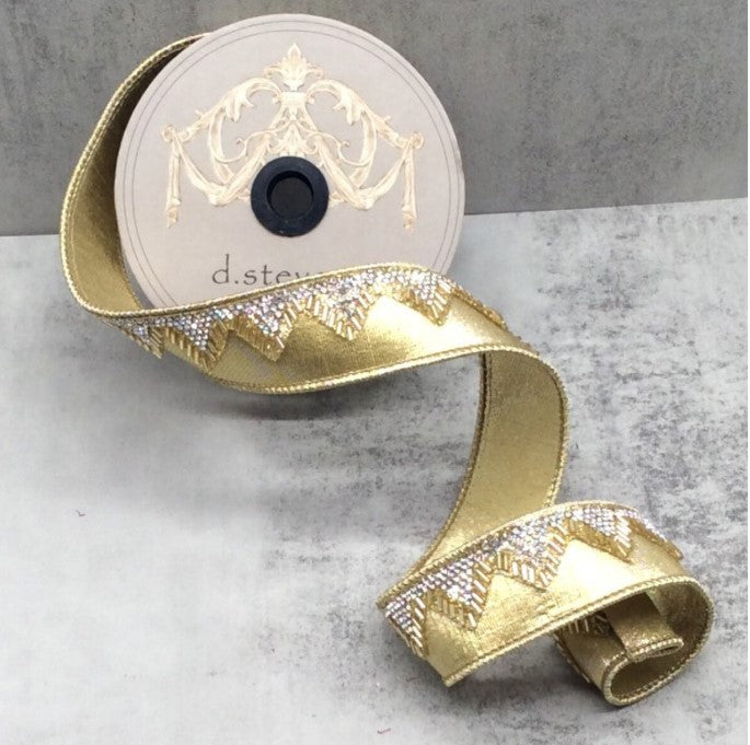 A gold-colored decorative ribbon with a metallic texture and a decorative pattern on it, placed on a gray surface.