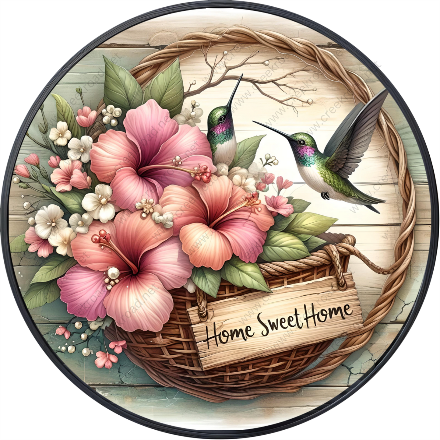 A wicker basket filled with pink and white flowers, with two hummingbirds perched on the basket. The basket is placed on a wooden surface, and there is a sign that reads "Home Sweet Home".