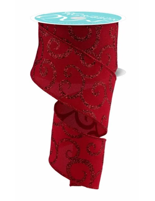 a red ribbon with a glittery pattern, hanging from a spool of the same ribbon.