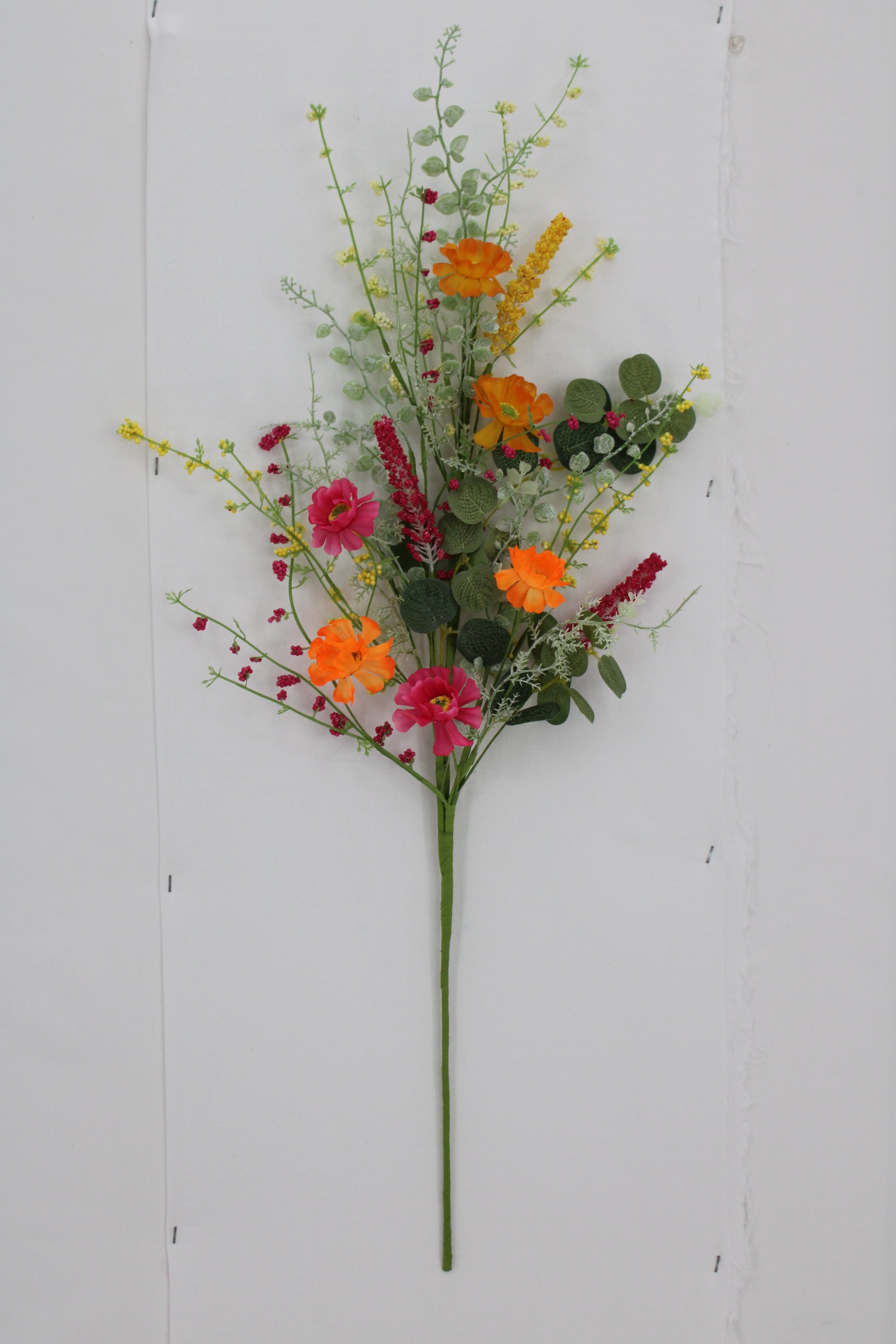 A bouquet of colorful flowers, including red, orange, and yellow blooms, is displayed against a white background.