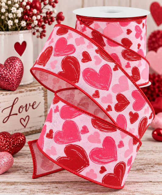 a pink and red heart-patterned ribbon, a white vase with red flowers, and some red and pink glitter hearts, all arranged on a wooden surface.