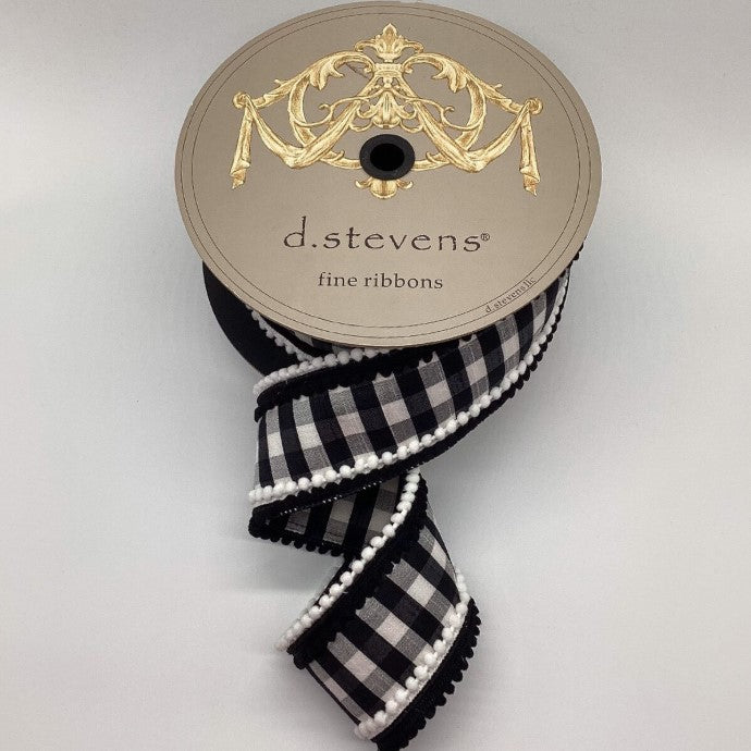A spool of ribbon with a decorative gold design on top, featuring a black and white checkered pattern and white trim.