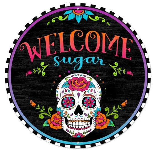 A colorful sign featuring a skull with floral decorations and the text "Welcome sugar" in a circular design.
