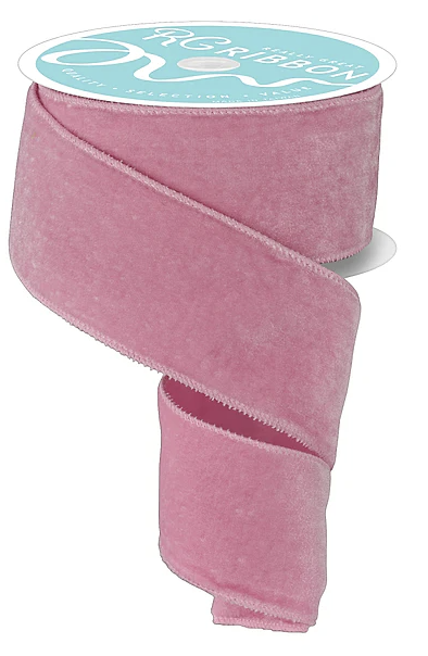 A roll of pink velvet ribbon with a label on top.