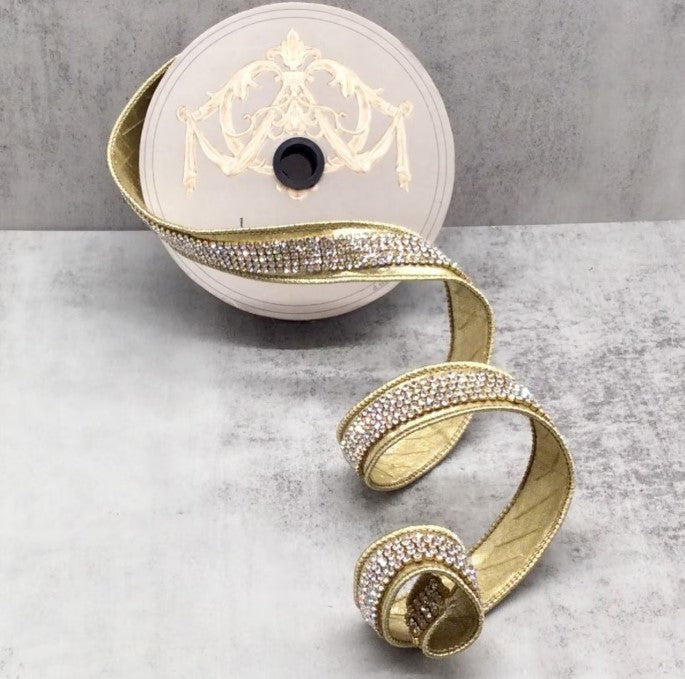 a gold ribbon with rhinestones, which is coiled and placed on a gray surface.