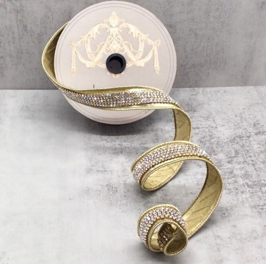 a gold ribbon with rhinestones, which is coiled and placed on a gray surface.