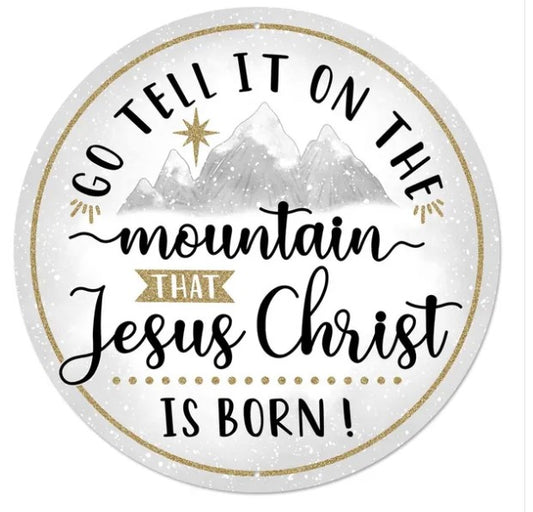 a circular design with a mountain and a star in the background, along with the text "Go Tell It On The Mountain That Jesus Christ Is Born!" written in a decorative font.