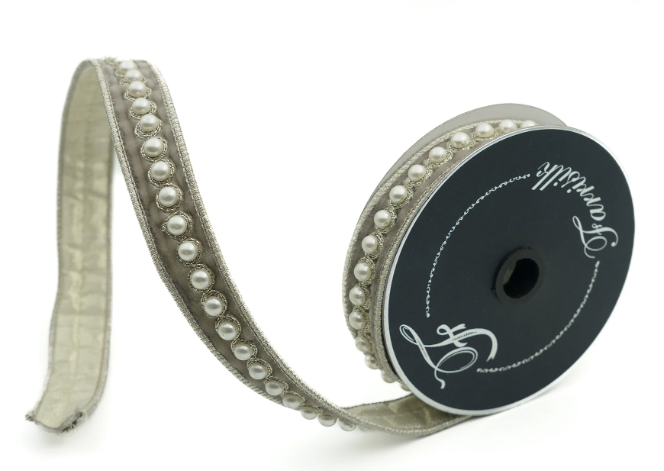 A silver-colored ribbon with a decorative beaded pattern and a black spool of ribbon with a white label.