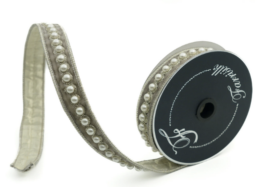 A silver-colored ribbon with a decorative beaded pattern and a black spool of ribbon with a white label.