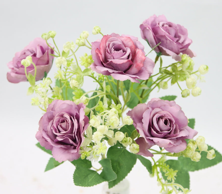 a vase filled with purple roses and white flowers