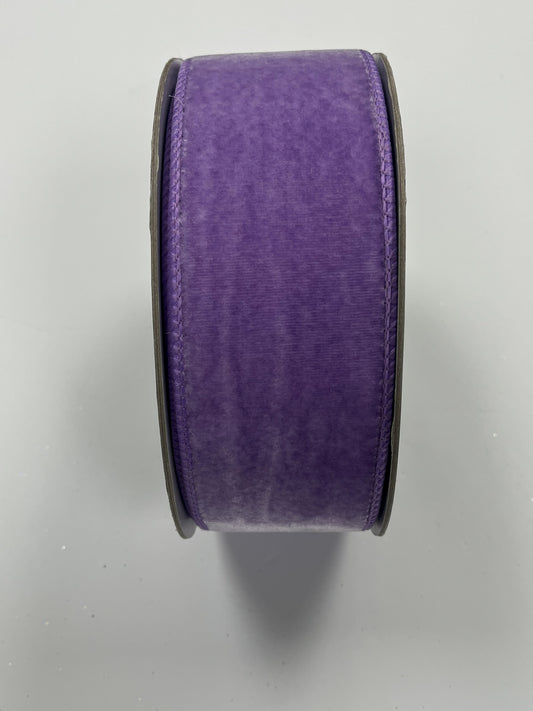 A roll of purple velvet ribbon is shown against a white background.