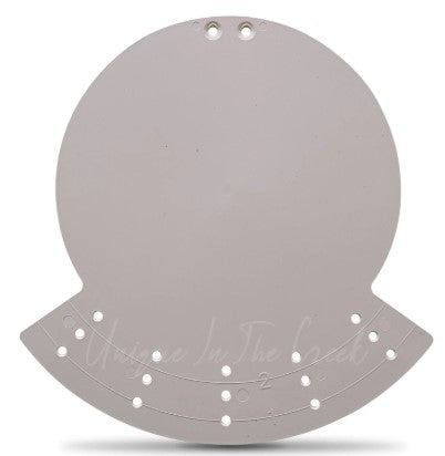A white, circular object with holes in it, which appears to be a measuring tool or a similar type of object.