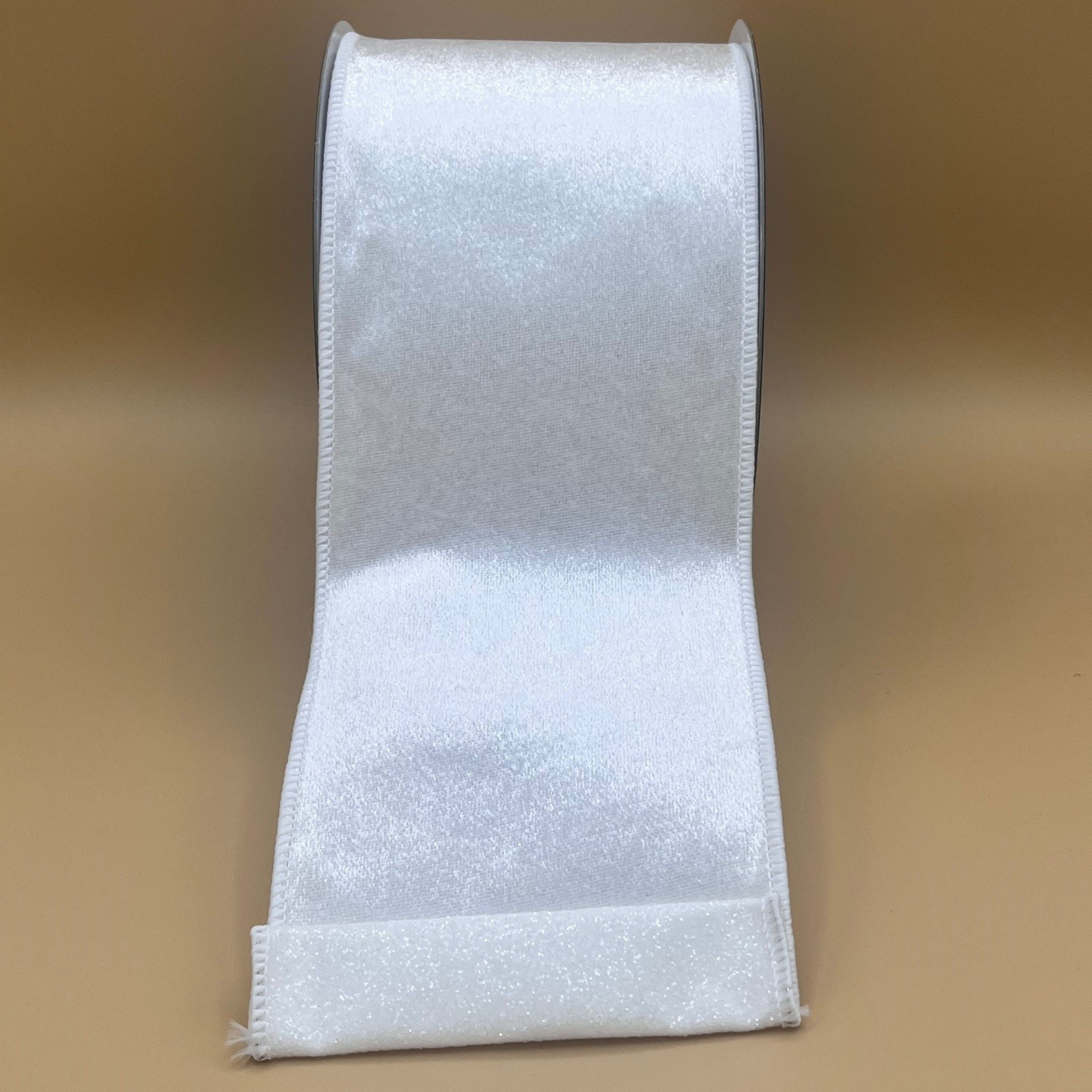 A roll of white satin ribbon against a beige background.