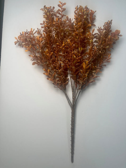 a branch with brown leaves, possibly from a tree, arranged in a way that creates a visually appealing composition.