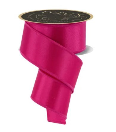 A roll of bright pink satin ribbon with a gold label.