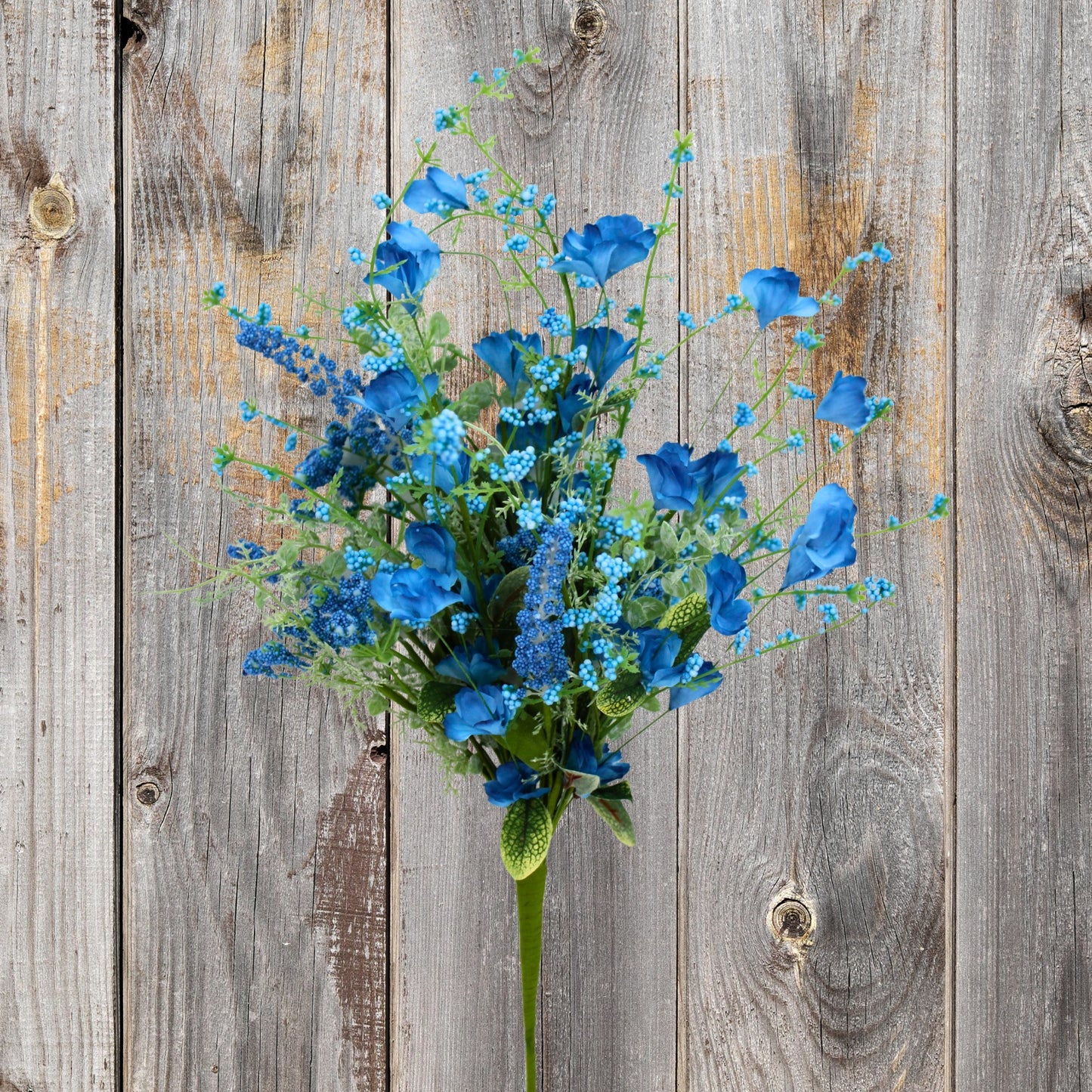 A bouquet of blue flowers and greenery is displayed against a weathered wooden background.