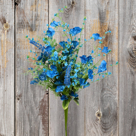 A bouquet of blue flowers and greenery is displayed against a weathered wooden background.