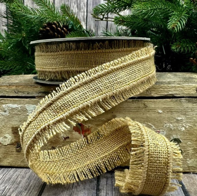 a burlap fringe ribbon with a fringed texture, placed on a wooden surface. The ribbon is tied in a decorative manner, and there is a pine tree in the background.