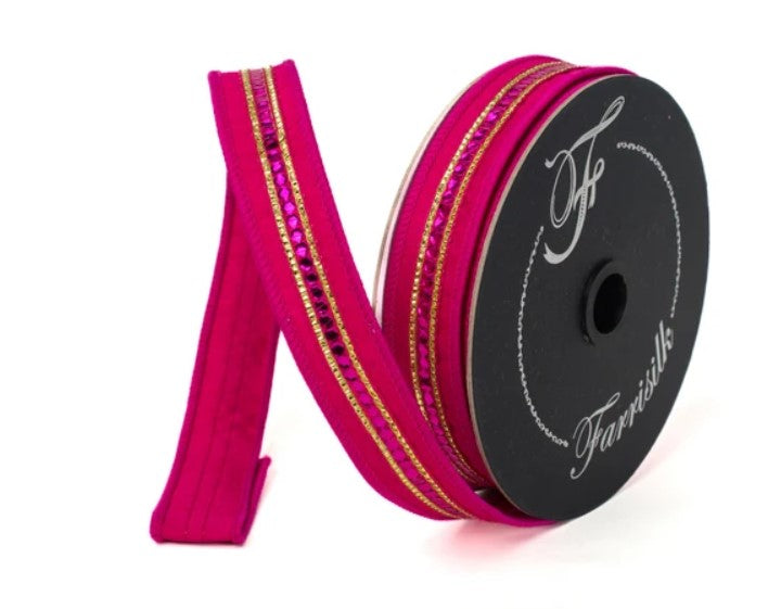 A spool of pink and gold decorative ribbon with rhinestones is shown against a white background.