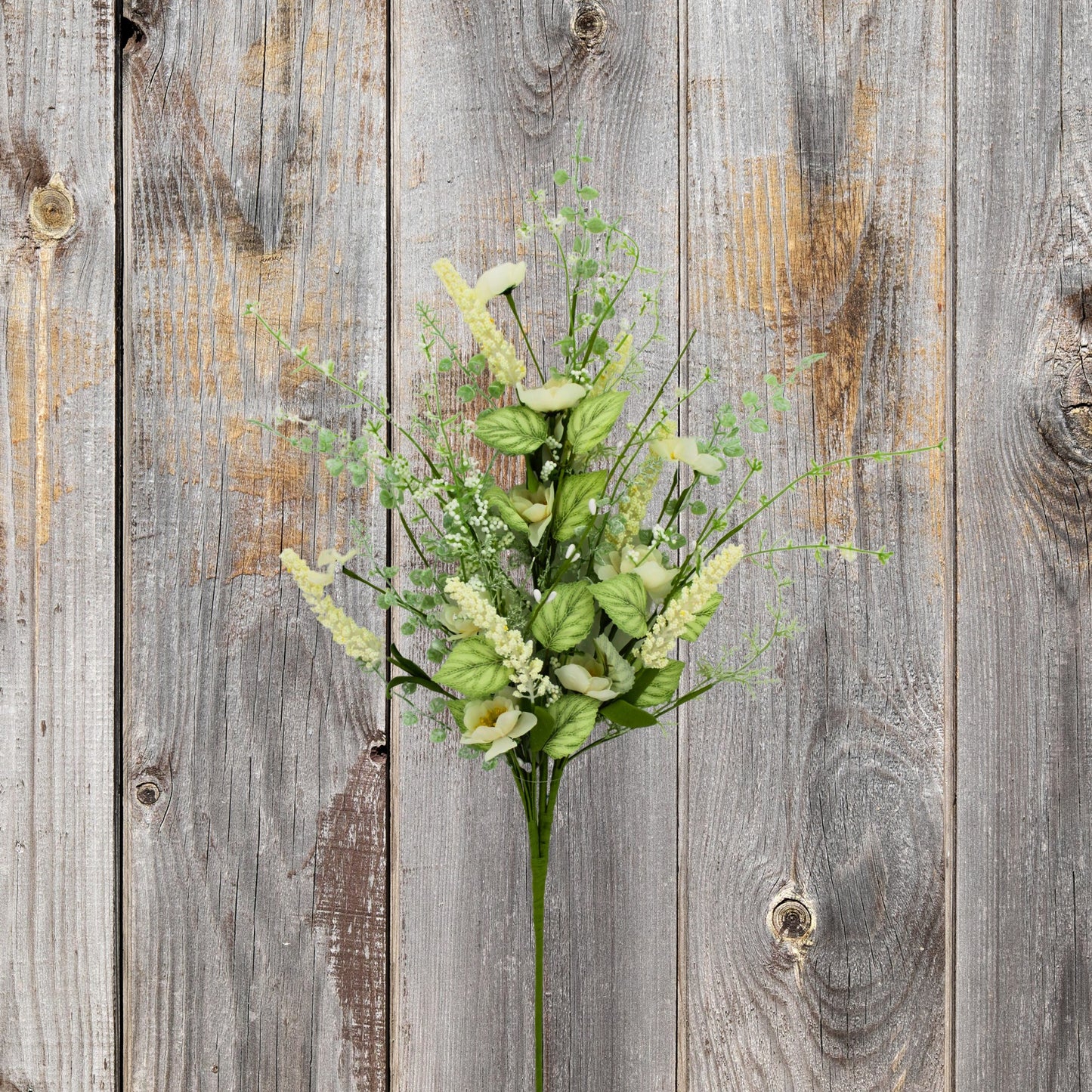 A bouquet of green and white flowers is displayed against a weathered wooden background.