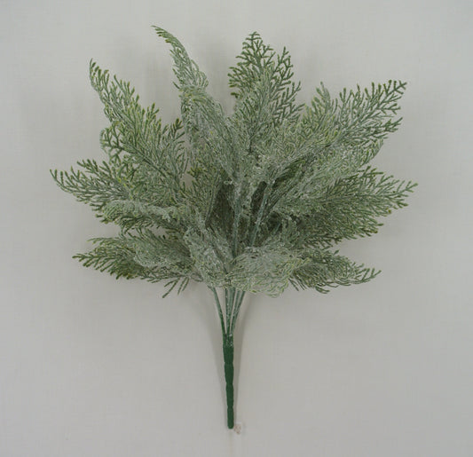 A bunch of green artificial fern-like leaves or branches against a plain white background.