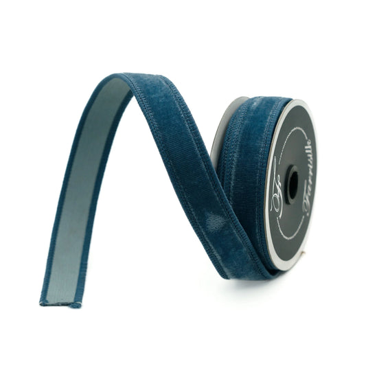 A roll of blue velvet ribbon with a white label on it, lying on a white background.