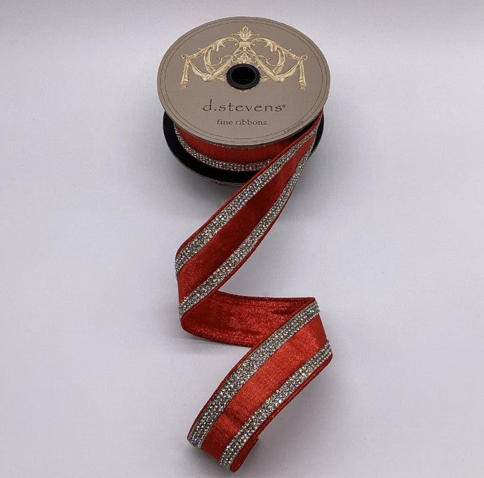 A spool of red ribbon with silver rhinestones is shown against a white background.